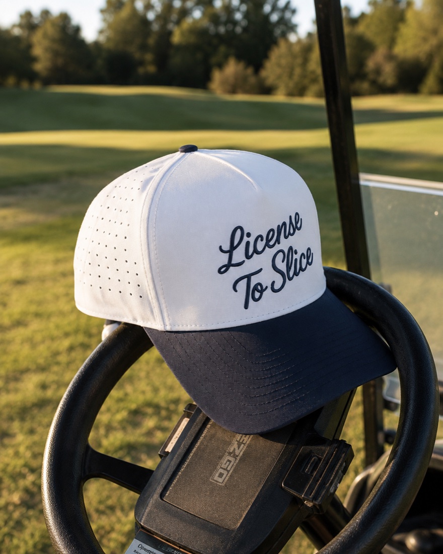 License To Slice golf cap resting on a cart steering wheel at golden hour